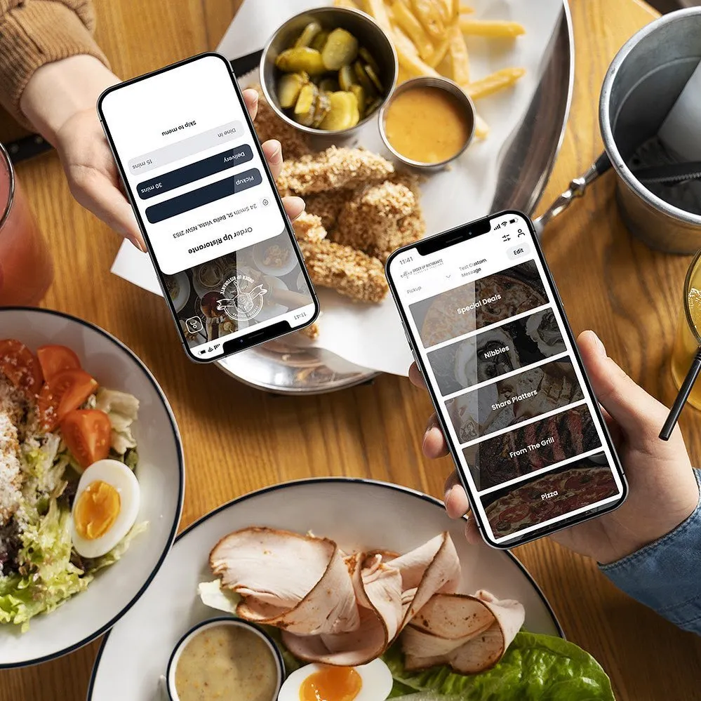 Two phones showing the OrderUp pickup and delivery menu above a table of shared food