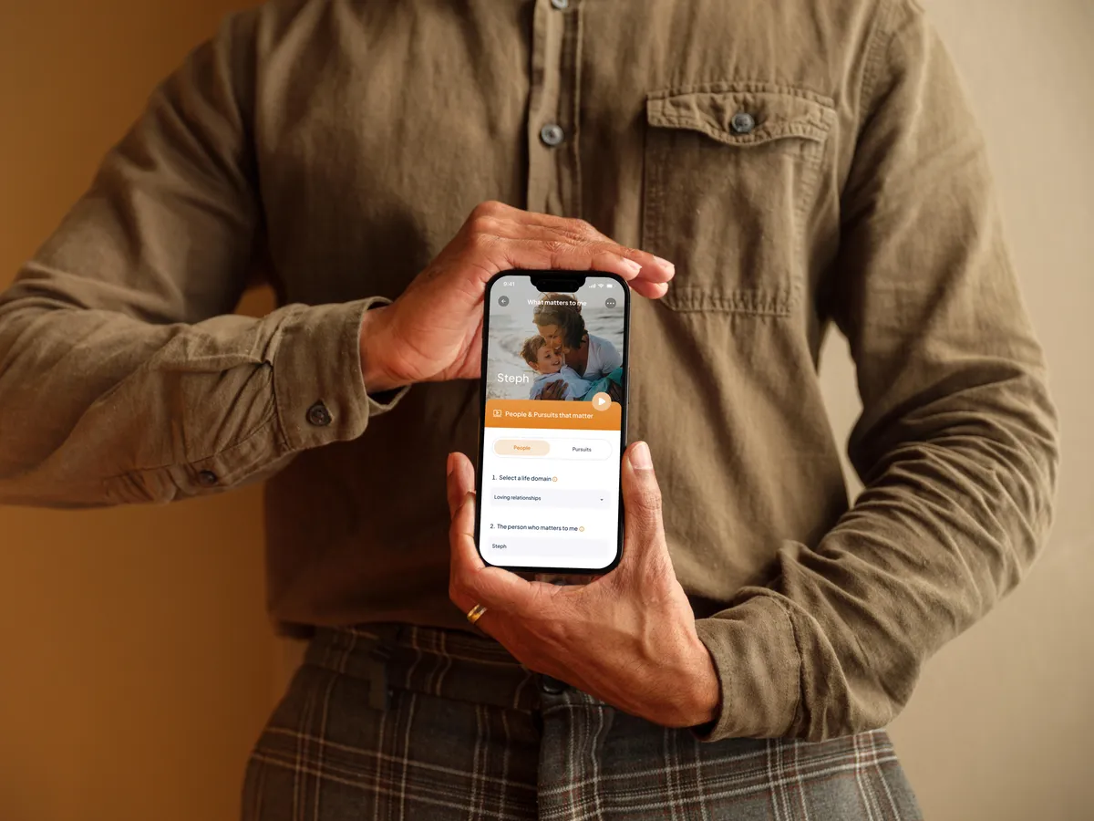 Person holding a phone displaying the Safe Guide Life ‘What matters to me’ screen