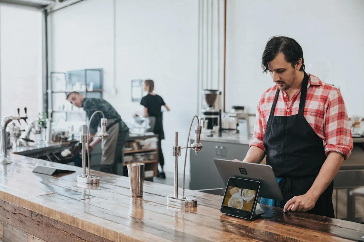 Barista using a POS tablet at a cafe counter